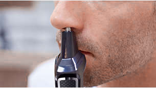 Hombre depilándose los pelos de la nariz con recortadora eléctrica